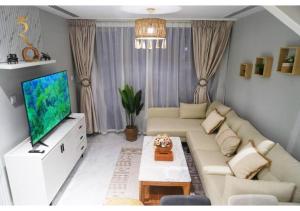 a living room with a couch and a flat screen tv at Jade Serenity 2BR - Pool, Gym & Comfort Near Masdar Park, Masdar City in Abu Dhabi