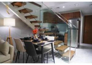 a living room with a table and a staircase at Jade Serenity 2BR - Pool, Gym & Comfort Near Masdar Park, Masdar City in Abu Dhabi