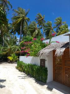 a building on the beach with flowers and palm trees at Futtaru Sands in Gaafaru