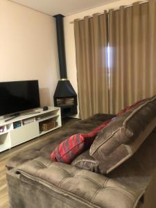 a couch in a living room with a flat screen tv at Refugio 4 suites com ar condicionado e piscina in Santa Bárbara do Rio Pardo