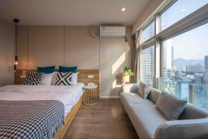 a bedroom with a bed and a couch and a window at Style INS High-Altitude River View Hotel (Chongqing Jiefangbei Pedestrian Street Branch) in Chongqing