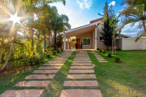 a stone path leading to a house with palm trees at Piscina Aquecida Casa no Thermas de Sta Bárbara in Santa Bárbara do Rio Pardo