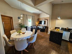 a dining room and living room with a table and chairs at Piscina Aquecida Casa no Thermas de Sta Bárbara in Santa Bárbara do Rio Pardo