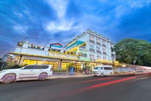 dos furgonetas blancas estacionadas frente a un edificio en Xaysomboun Hotel & SPA, en Vientiane