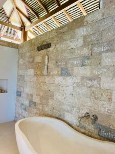 a bath tub in a room with a stone wall at Paradise in Lembongan awaits in Nusa Lembongan