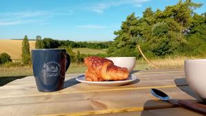 a table with a plate of croissant and a cup of coffee at Les tiny houses autonomes du val d'or in Fraignot-et-Vesvrotte