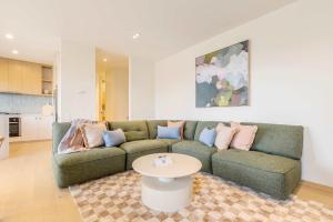a living room with a green couch and a table at Stylish Spacious Apartment in Malvern in Melbourne
