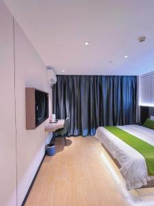 una camera da letto con un letto, una scrivania e una televisione di GreenTree Inn Express Guangxi Nanning Mingyang Avenue Nanning Airport a Nanning