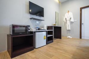 a living room with a television and a dress shirt hanging on a wall at U- Homehotel Nakhonpanom in Nakhon Phanom +21 photos