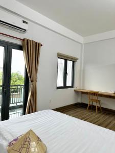 a bedroom with a bed and a desk and windows at Gạo Homestay-Hue in Hue