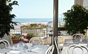 restauracja ze stołami i krzesłami z widokiem na ocean w obiekcie Hotel Ambassador w mieście Marotta
