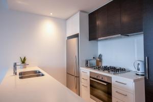a kitchen with a sink and a stainless steel refrigerator at Prima Tower - Premium Apartment with City and Flames Views in Melbourne +31 photos