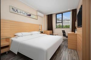 a bedroom with a large white bed and a desk at City Comfort Inn Wuhan Huanghe Tower Shouyi Metro Station in Wuhan