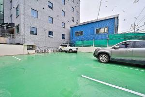 a green parking lot with a car parked in front of a building at Namunuelbo Hotel Uhbang Branch in Sambang-dong