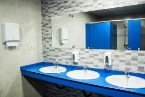 uma casa de banho com três lavatórios e um balcão azul em De Camino em Arzúa
