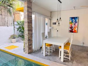a dining area with a table and chairs next to a swimming pool at Palm Villa 5 Seminyak Center in Seminyak
