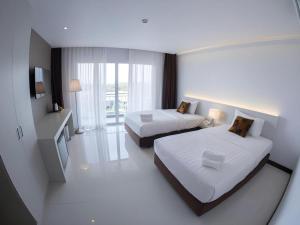 a hotel room with two beds and a television at Chaisaeng Villa in Sing Buri