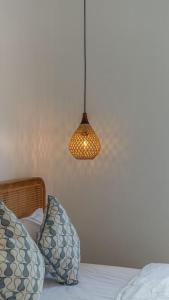 a light hanging over a bed with two pillows at The Lotus Backyard Uluwatu in Badung