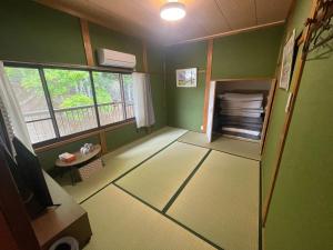 a room with green walls and a tv and a window at みなと館 華 in Sukumo