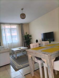 a living room with a wooden table and a tv at Johari Suites and Shared Studio Westlands in Nairobi
