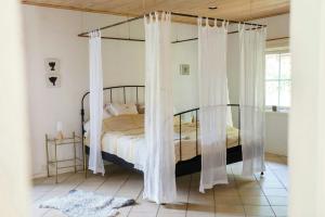 een slaapkamer met een hemelbed en witte gordijnen bij Creative Hideaway By Hållsviken Bay in Trosa