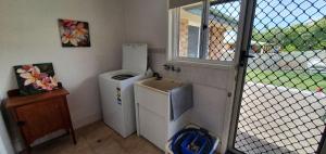 eine kleine Küche mit einem Kühlschrank und einem Fenster in der Unterkunft Rainbow Cottage - Rainbow Beach. Pets welcome in Rainbow Beach + 3 Fotos