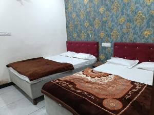 una habitación con dos camas y una pared en Hotel Muskan Villa, en Ujjain
