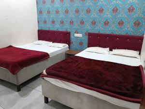 Dos camas en una habitación de hotel con sábanas rojas. en Hotel Muskan Villa, en Ujjain