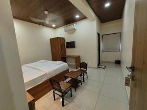 a bedroom with a bed and a table and chairs at Hotel Queen Inn in Pune