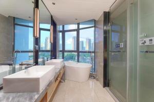 ein Badezimmer mit zwei Waschbecken, einer Badewanne und einer Dusche in der Unterkunft Echarm Hotel Wuxi Zhongnan Road Ancient Canal in Wuxi + 228 Fotos