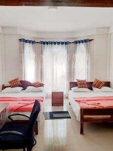 a bedroom with two beds and a chair and a window at Malaka Inn Bandarawela in Bandarawela