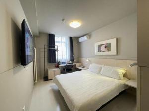 a bedroom with a white bed and a television at Jinjiang Inn Beijing Huairou Qingchun Road Wanda Plaza in Beijing