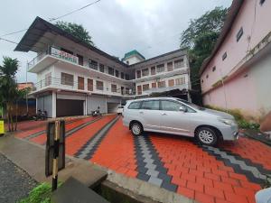 a silver car parked in front of a building at Josco Residency Karthikapuram in Paithalmala