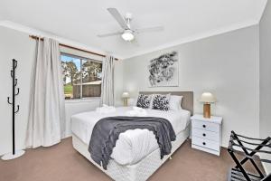 a white bedroom with a bed and a window at Andres Farm Cottage in Broke