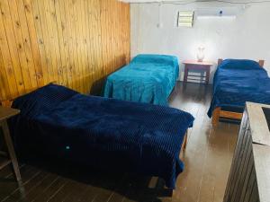 zwei Betten in einem Zimmer mit blauen Laken darauf in der Unterkunft Iberá in Mercedes