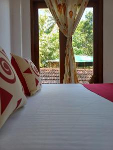 a bedroom with a white bed with a window at Cosmic power in Mirissa +2 photos