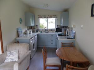 a small kitchen with a table and a dining room at Sea Breeze Bungalow - Welcombe North Devon in Welcombe
