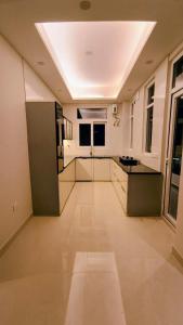 a large kitchen with white walls and a ceiling at Stylish 2 BHK Near ISBT & Rajpur Road in Dehradun +4 photos