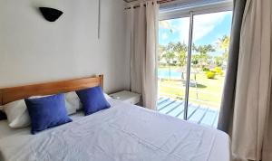 a bedroom with a bed with blue pillows and a window at Maison Lakazbleu - 100m plage Mont Choisy in Mont Choisy +39 photos