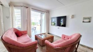 a living room with two couches and a tv at Maison Lakazbleu - 100m plage Mont Choisy in Mont Choisy