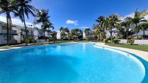 a large blue swimming pool in front of some apartments at Maison Lakazbleu - 100m plage Mont Choisy in Mont Choisy