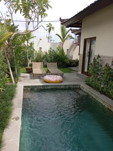 a swimming pool with two chairs next to a house at Villa Brahmari in Ubud