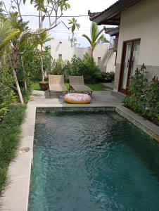 a swimming pool with two chairs next to a house at Villa Brahmari in Ubud +15 photos