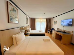 a hotel room with a large bed and a desk at Vista Mar Beach Resort and Country Club in Mactan
