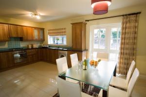 a kitchen with a dining table and white chairs at Kenmare Bay Hotel Holiday Homes in Kenmare