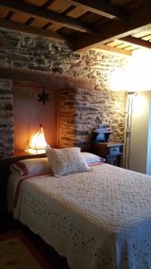 1 dormitorio con 1 cama con pared de piedra en A Lareira, en Chan de Vilar