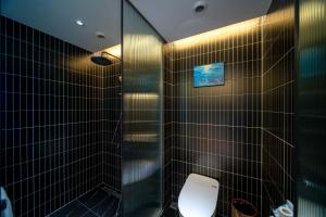 une salle de bain avec toilettes et douche en verre dans l'établissement Yasong Jianwen Resort Hotel, à Diaolongzui