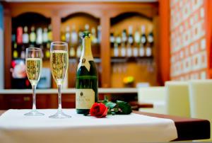 eine Flasche Champagner und zwei Gläser auf dem Tisch in der Unterkunft Villa Rossa Hotel in Chişinău