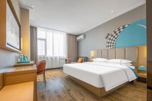 a bedroom with a large white bed and a desk at City Comfort Inn Dangtu High Speed East Railway Station RT-Mart in Ma'anshan