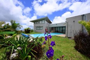 una casa con un cortile con fiori viola e una piscina di 3 in suite bedrooms Villa in Avalon Golf Estate a Bois Chéri